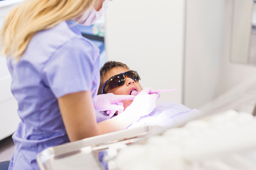 Dentista aplicando técnica de sellado de dientes en niño