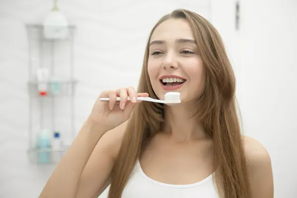 Mujer joven usando crema para sensibilidad dental